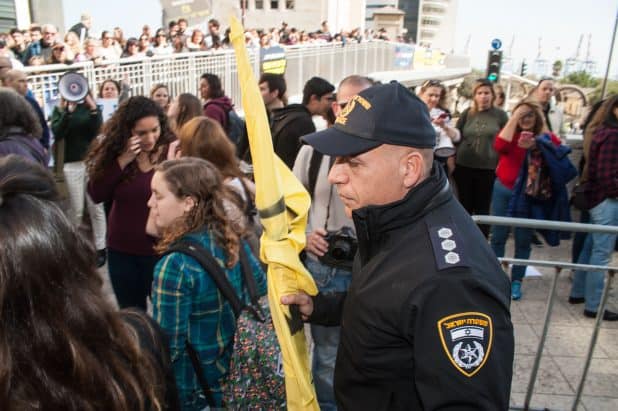 הפגנה בדרישה לפינוי מיכל האמוניה. שוטר מחרים את דגלי "חיזבאללה". צילום: דורון גולן