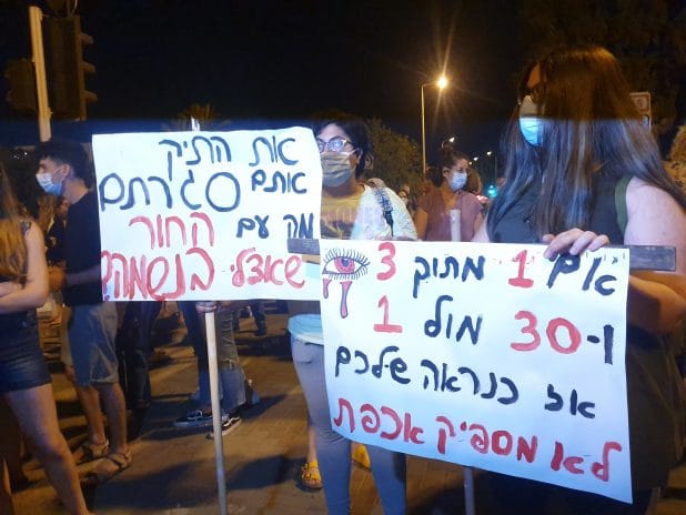 בזמן ההפגנה מרימים שלטים | צילום: איילת קדם